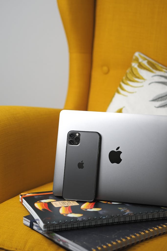 A laptop and an iphone sitting on a yellow chair