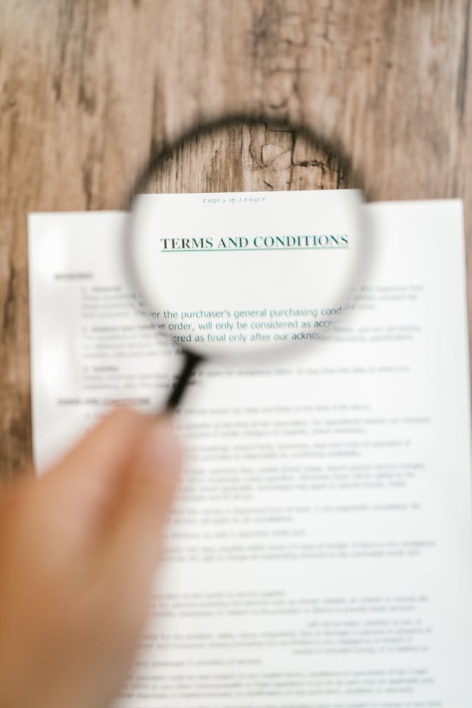 Person Holding A Magnifying Glass Above A Document